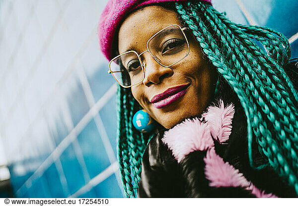 Portrait of smiling braided hair woman wearing eyeglasses and pink lipstick