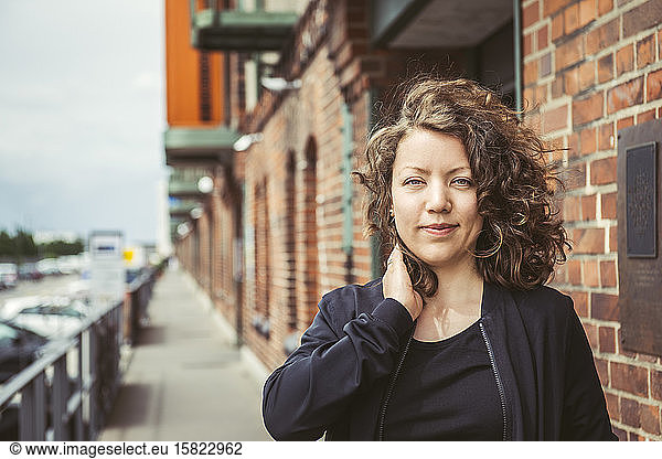 Portrait of smiling brunette woman in front of a brick building