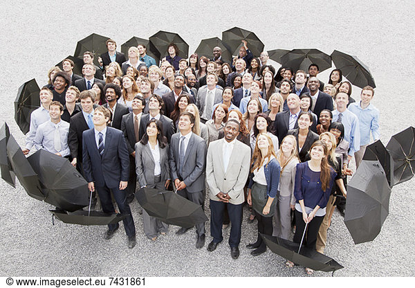 Portrait of smiling business people with umbrellas looking up