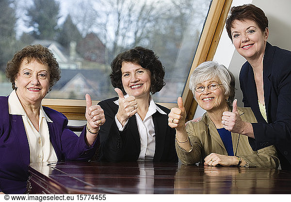 Portrait of smiling business women sitting by a table.