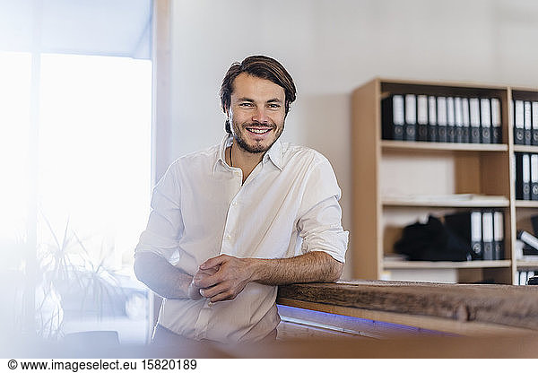 Portrait of smiling businessman in wooden open-plan office