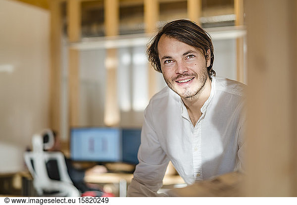 Portrait of smiling businessman in wooden open-plan office