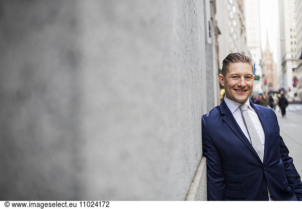 Portrait of smiling businessman leaning on wall