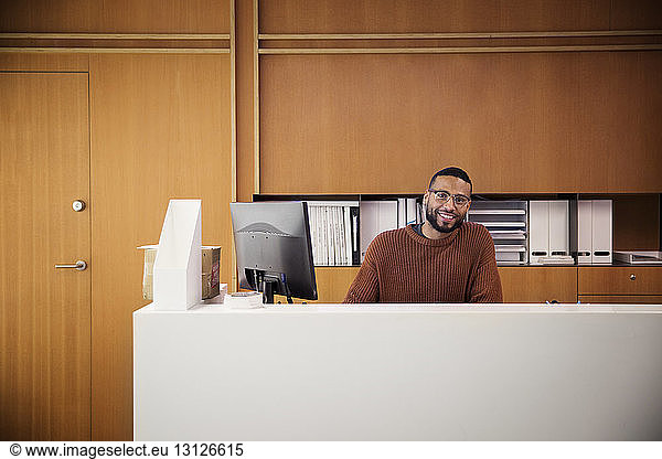 Portrait of smiling businessman sitting by desktop computer in office