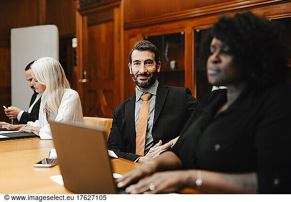 Portrait of smiling businessman sitting with colleagues in conference room