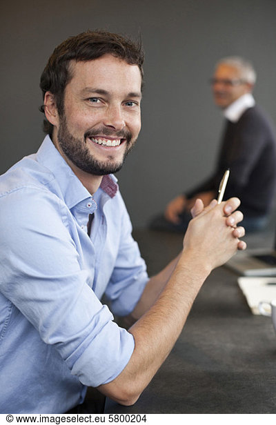 Portrait of smiling businessman with colleague in background