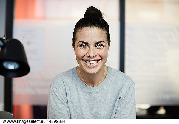 Portrait of smiling businesswoman sitting in creative office