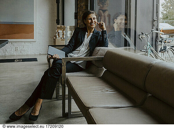 Portrait of smiling businesswoman sitting on sofa at office