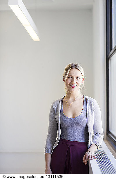 Portrait of smiling businesswoman standing by window in new office