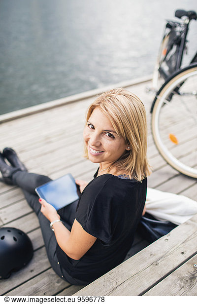 Portrait of smiling businesswoman using digital tablet while sitting on steps