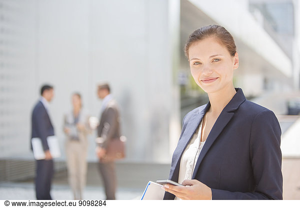 Portrait of smiling businesswoman with cell phone outdoors