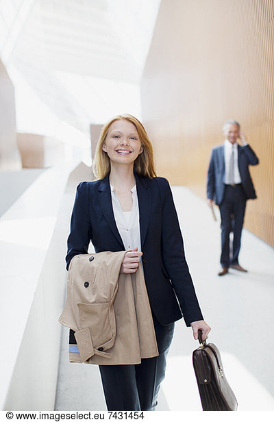 Portrait of smiling businesswoman with coat and briefcase