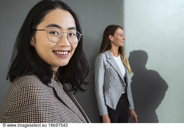 Portrait of smiling businesswoman with colleague in background