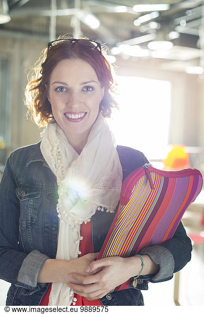 Portrait of smiling casual businesswoman holding laptop case