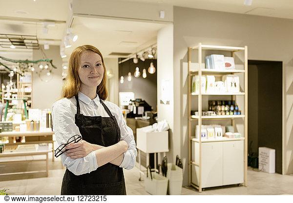 Portrait of smiling confident owner standing with arms crossed at design store