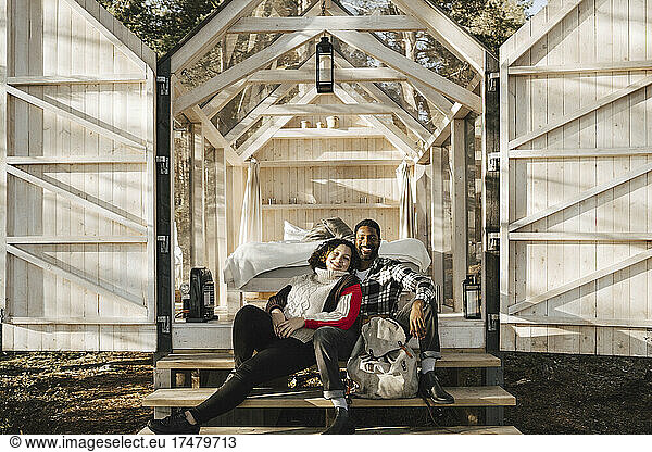 Portrait of smiling couple sitting on cottage steps