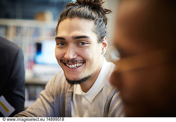 Portrait of smiling creative businessman sitting by male in office
