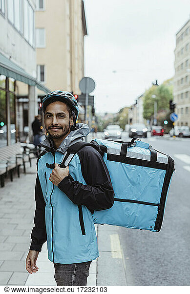 Portrait of smiling delivery man on sidewalk in city
