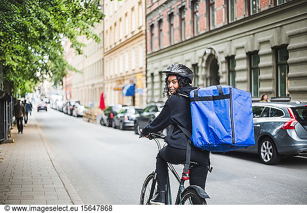 Portrait of smiling delivery woman with bicycle on street in city