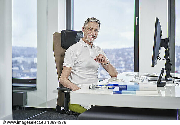 Portrait of smiling doctor sitting at desk in medical practice