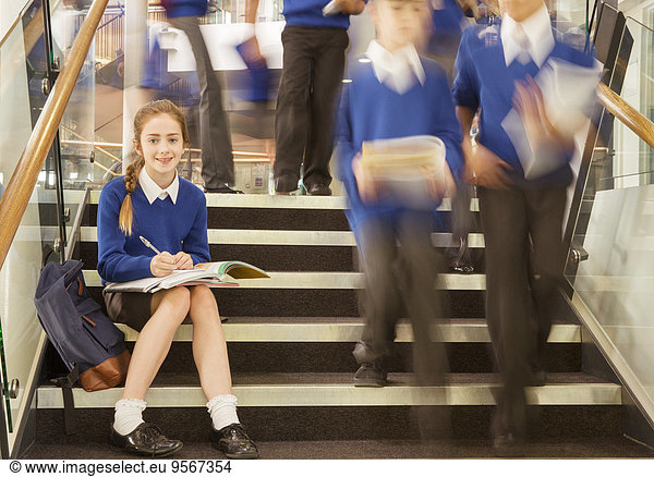 Portrait of smiling elementary school girl sitting on steps in school