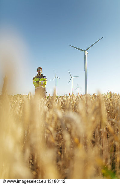 Portrait of smiling engineer standing in a field at a wind farm