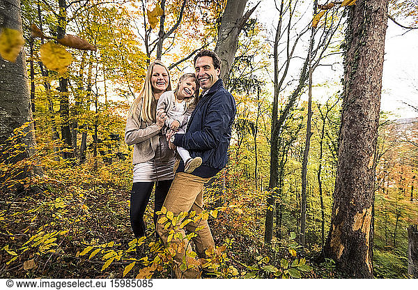 Portrait of smiling family standing in forest during autumn