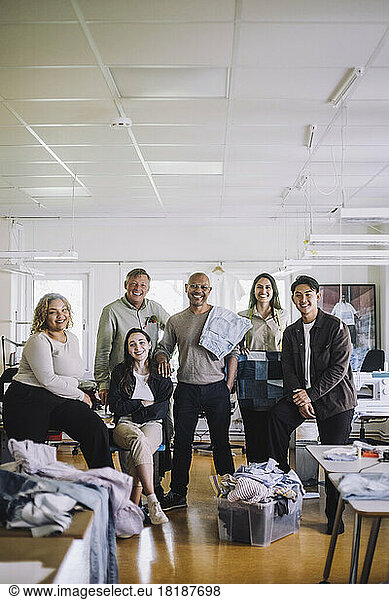 Portrait of smiling fashion designer and colleagues standing together at workshop