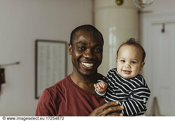 Portrait of smiling father and toddler son at home