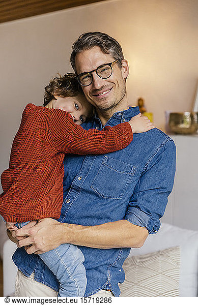 Portrait of smiling father carrying daughter at home