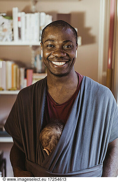 Portrait of smiling father with toddler son in baby carrier
