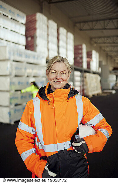 Portrait of smiling female blue-collar worker in protective workwear at factory