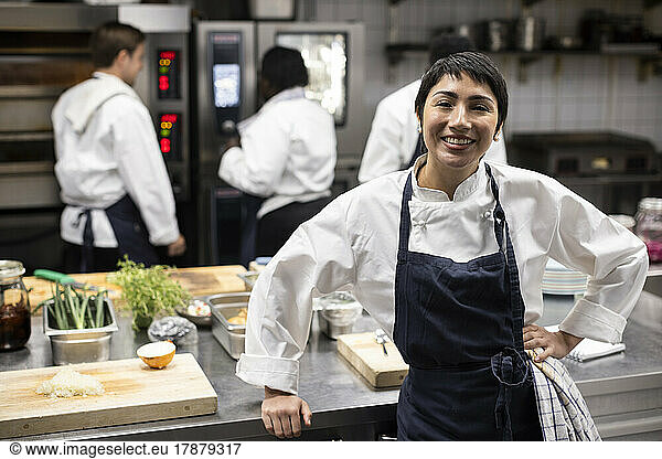 Portrait of smiling female chef standing in commercial kitchen of restaurant