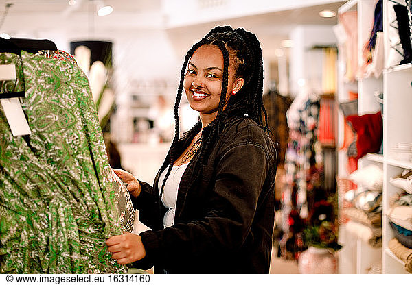 Portrait of smiling female customer standing at fashion store