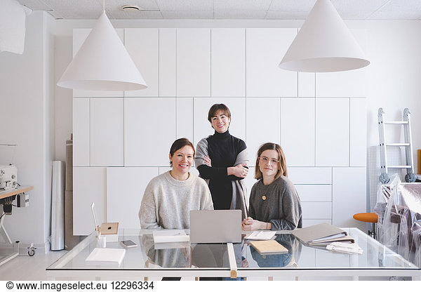 Portrait of smiling female design professionals at desk in workshop