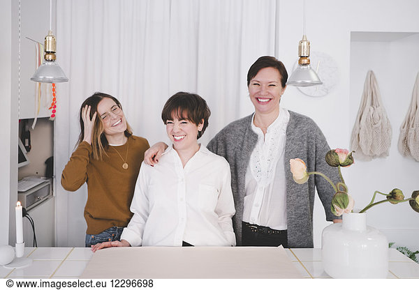 Portrait of smiling female design professionals standing at desk in studio
