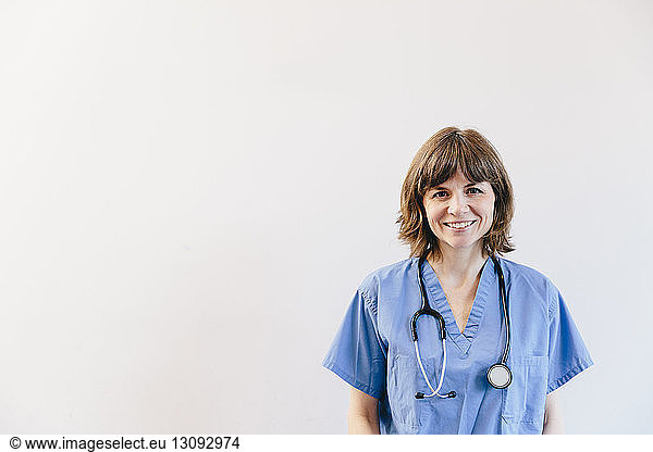 Portrait of smiling female doctor with stethoscope standing against white background