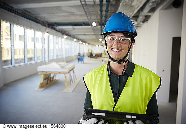 Portrait of smiling female engineer in protective workwear at construction site