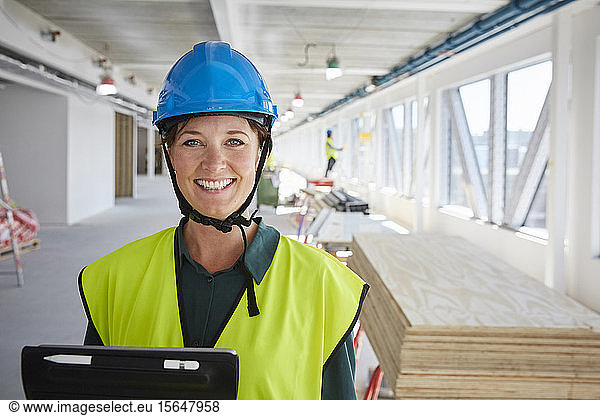 Portrait of smiling female engineer in reflective clothing at construction site