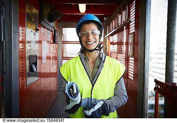 Portrait of smiling female engineer in reflective clothing at construction site