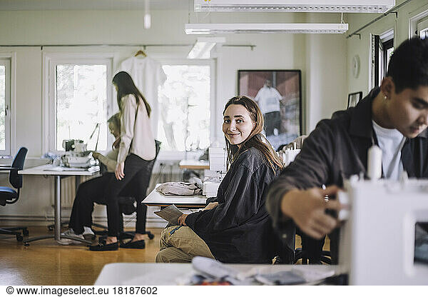 Portrait of smiling female fashion designer sitting at workshop