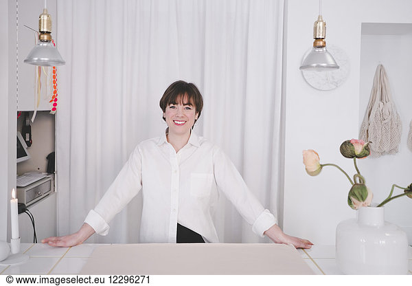 Portrait of smiling female interior designer standing at desk in studio