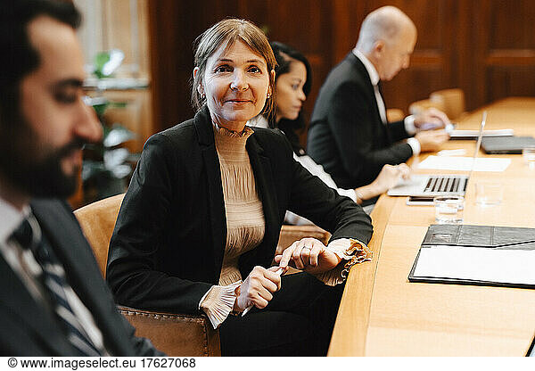 Portrait of smiling female lawyer in board room with colleagues during meeting