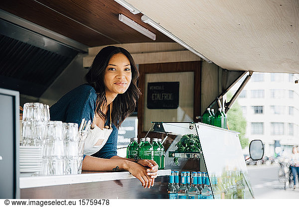 Portrait of smiling female owner standing in food truck
