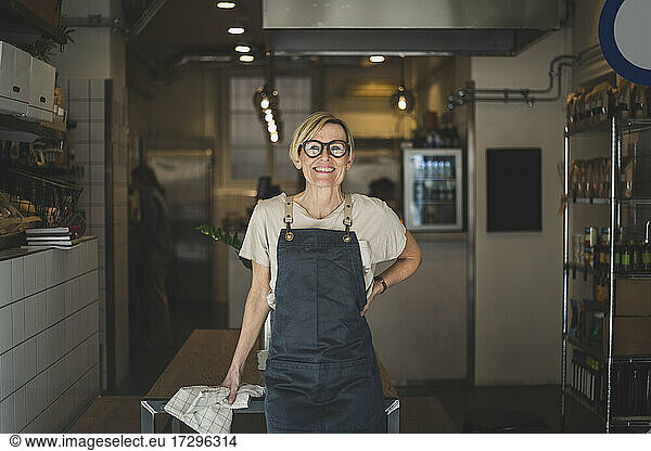 Portrait of smiling female owner with hand on hip in store
