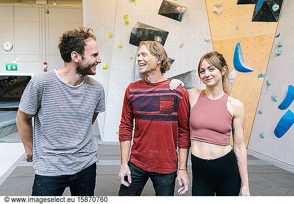 Portrait of smiling female standing with coach and male student in gym