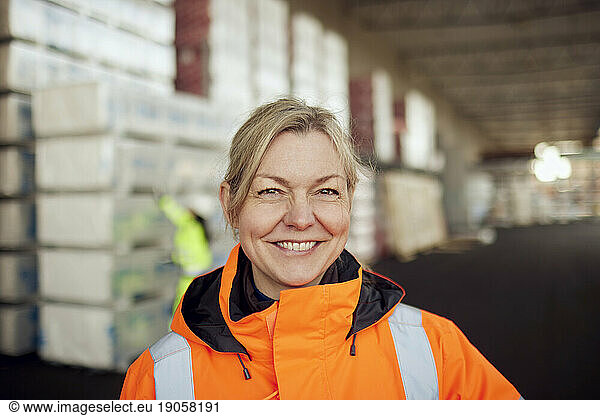 Portrait of smiling female worker in protective workwear at industry