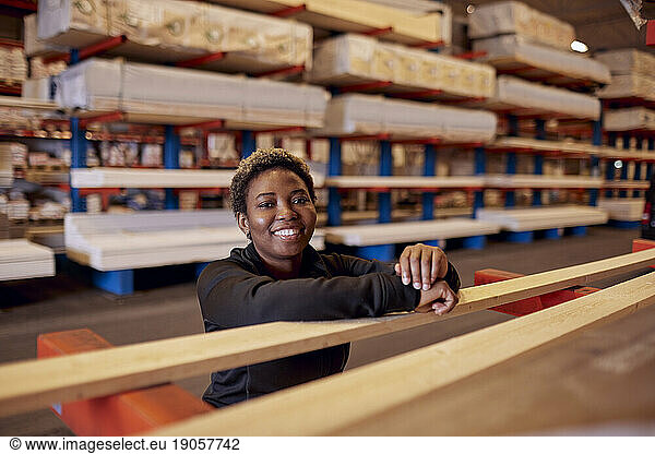 Portrait of smiling female worker leaning on plank in lumber industry