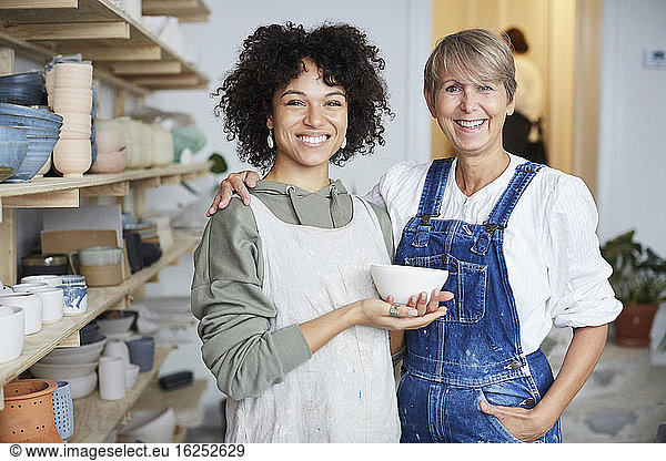 Portrait of smiling females with bowl in pottery class