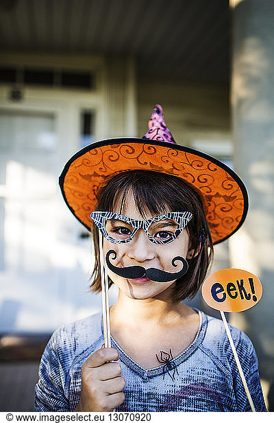 Portrait of smiling girl holding props enjoying during Halloween party
